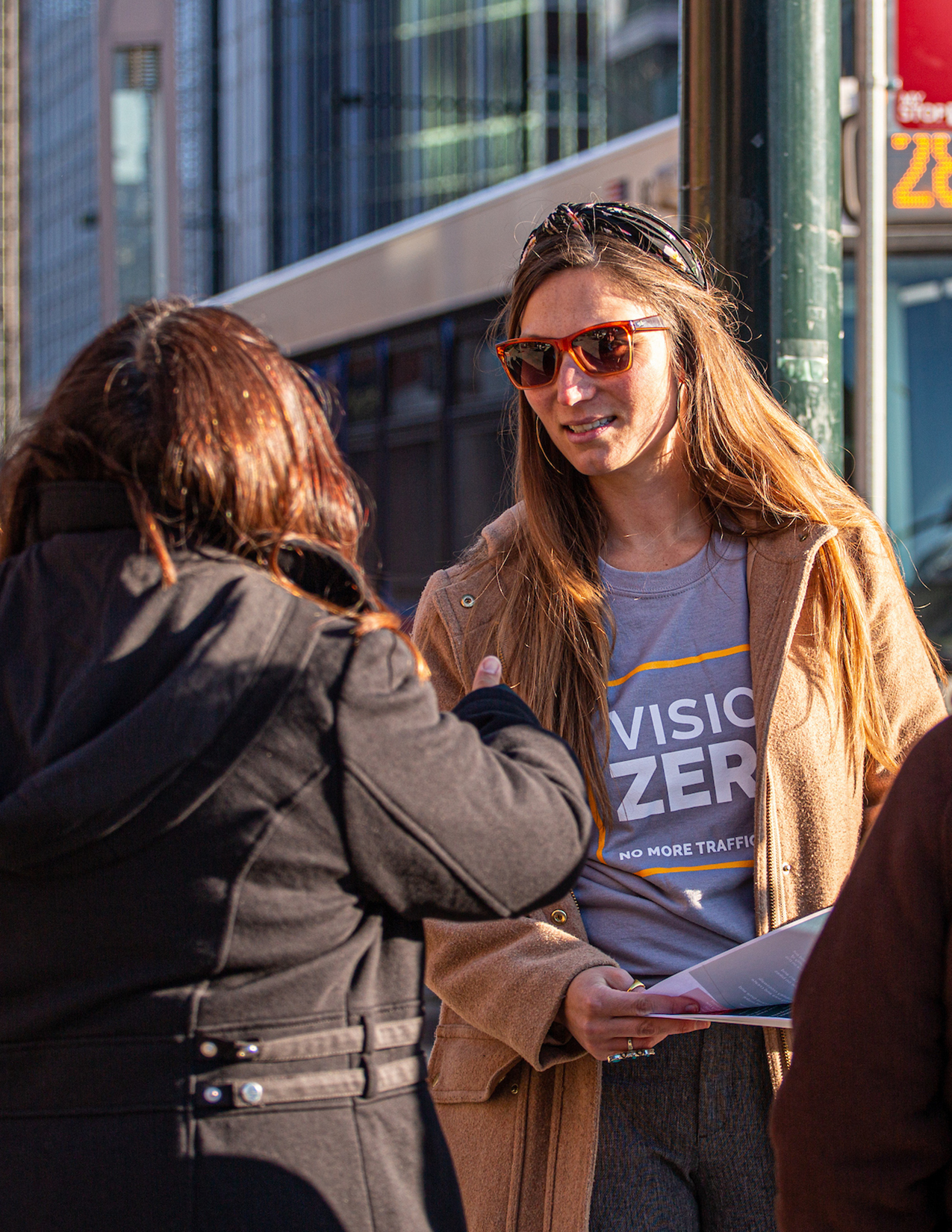 Residents on the street discussing Vision Zero initiatives at a local bus stop.