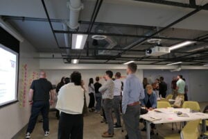 Participants discuss and rearrange sticky notes on the walls of the training room.