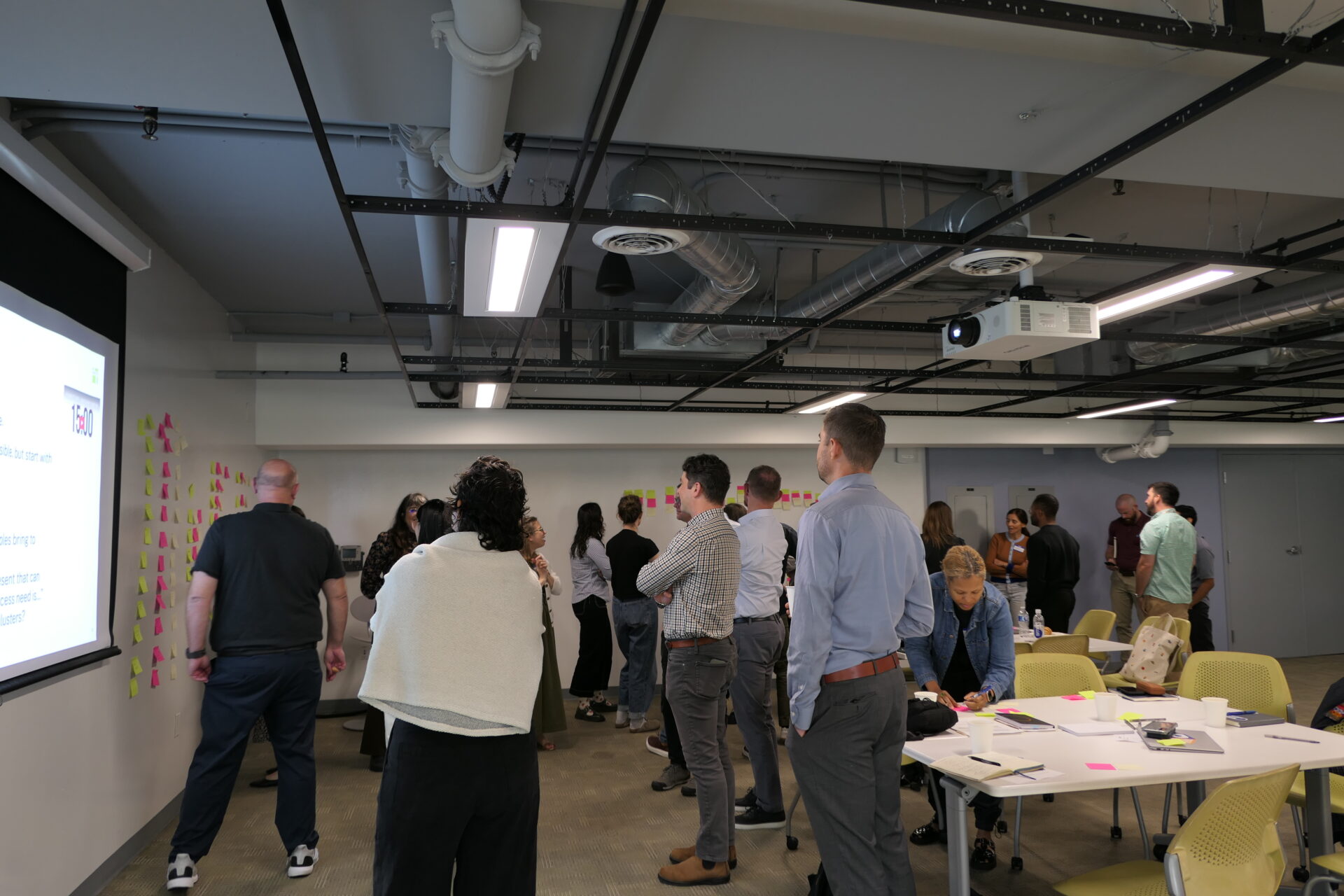 Participants discuss and rearrange sticky notes on the walls of the training room.