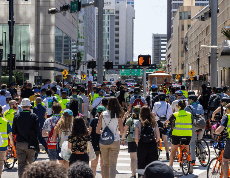 Large group of people walking and on bikes crossing the street to start walkshops at the Designing Cities Conference in Miami.