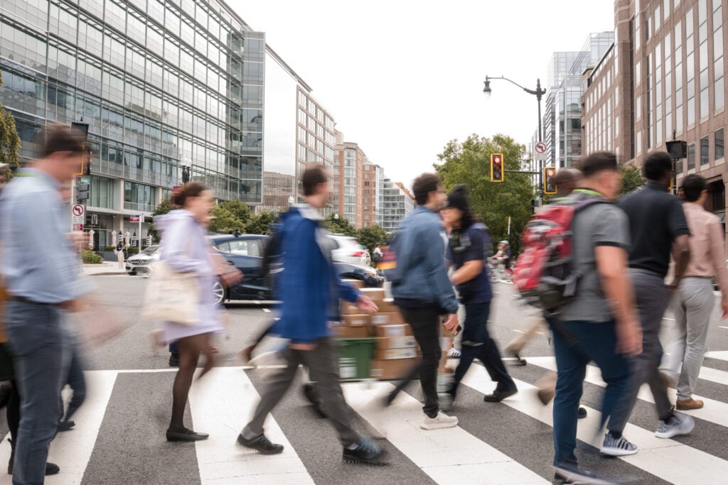 Attendees of Designing Cities 2025 in Washington DC cross the street at a crosswalk