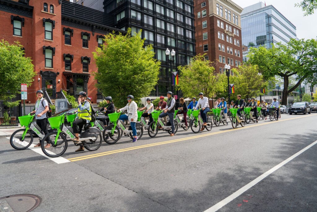 About a dozen people ride bikes on a DC street at Designing Cities 2025 in Washington DC