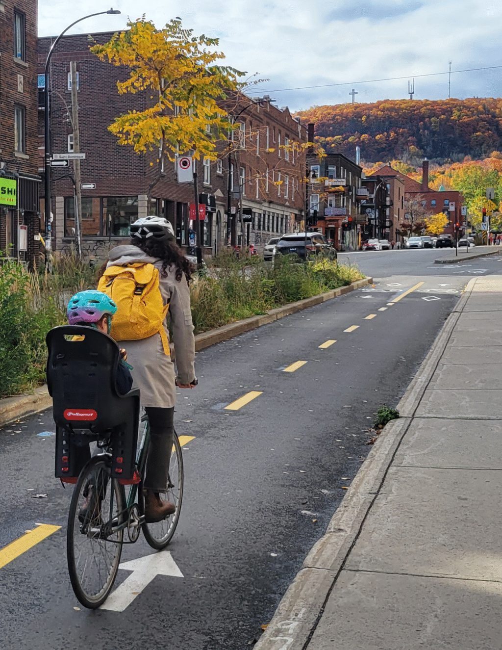 Adult with child in a bikeseat is biking in a two-way protected bike lane