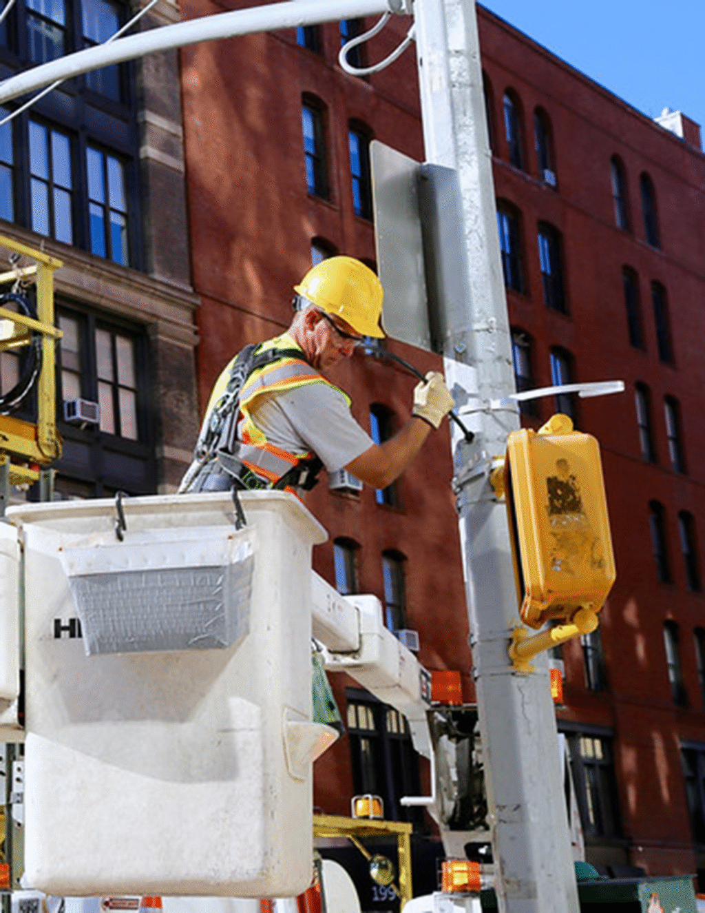 Technicians in a bucket truck work on traffic signals at an intersection.