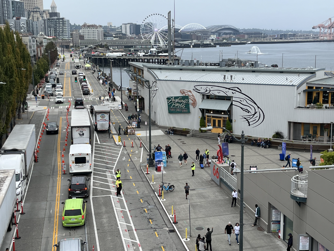 A birds-eye view of a waterfront street in Seattle where commercial loading to a pier-based business is occurring as designed, across a protected bike lane.