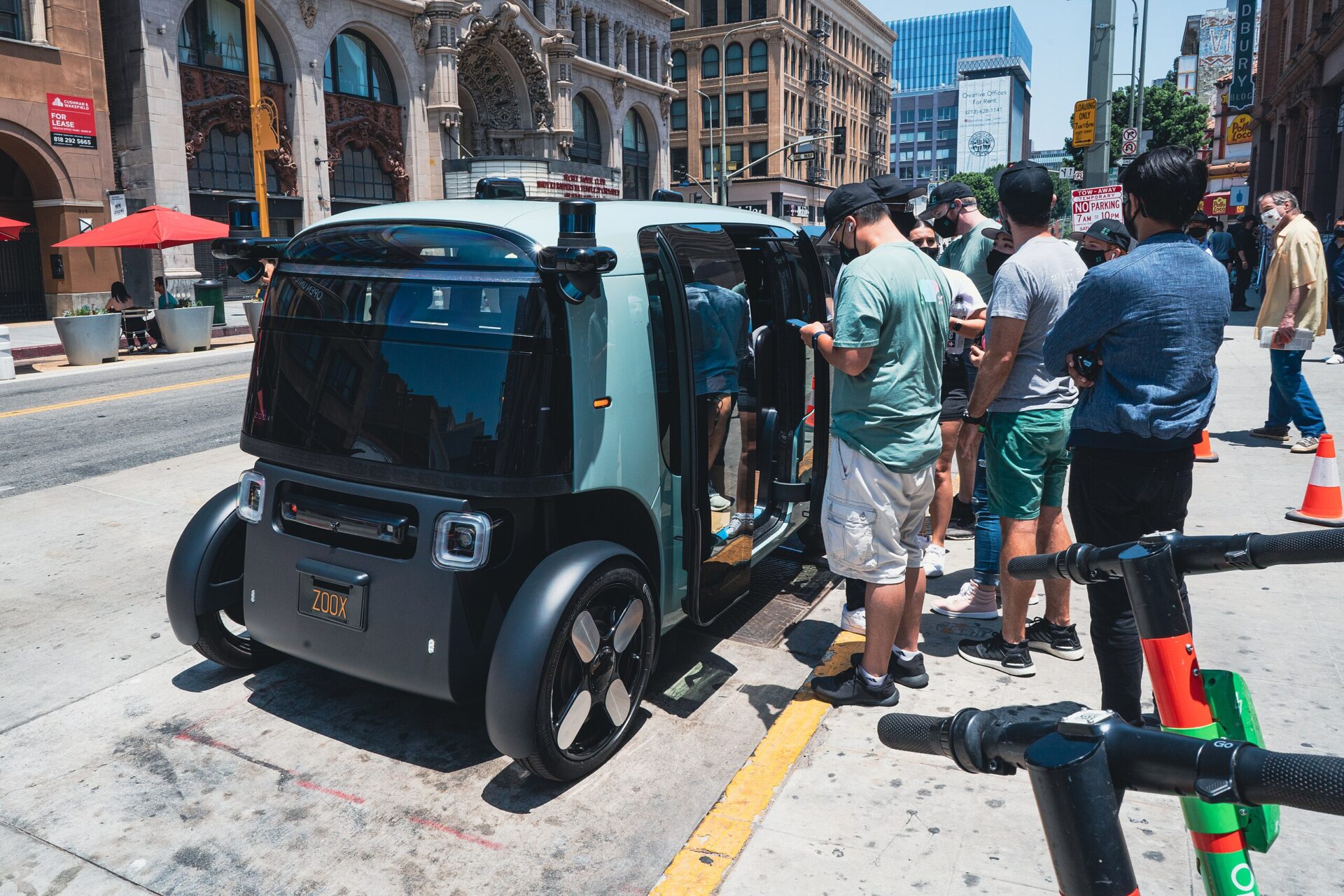 A group of people stand on the curb, waiting to enter an autonomous vehicle.