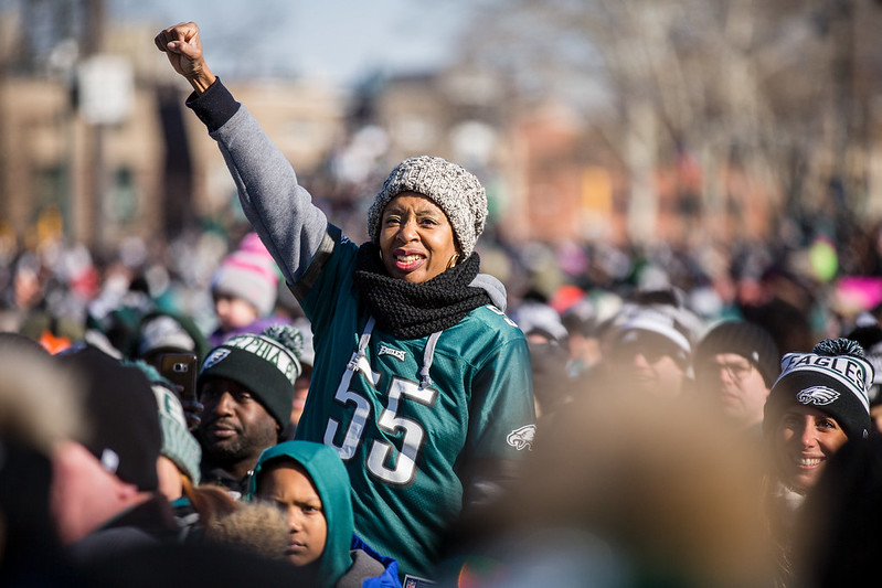 A woman wearing a Philadelphia Eagles jersey raises her fist to celebrate the team's win at the 2018 championship parade.